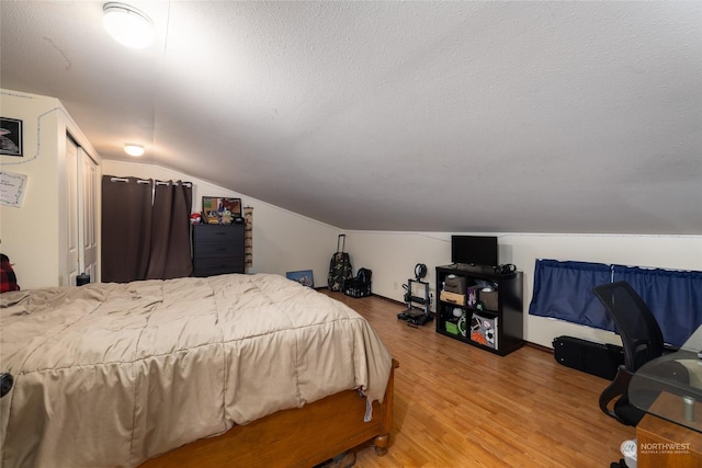 bedroom featuring hardwood / wood-style floors, a textured ceiling, and lofted ceiling