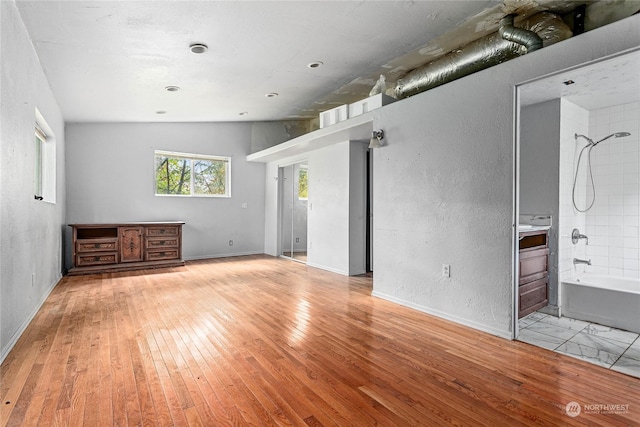 unfurnished living room with lofted ceiling and light wood-type flooring