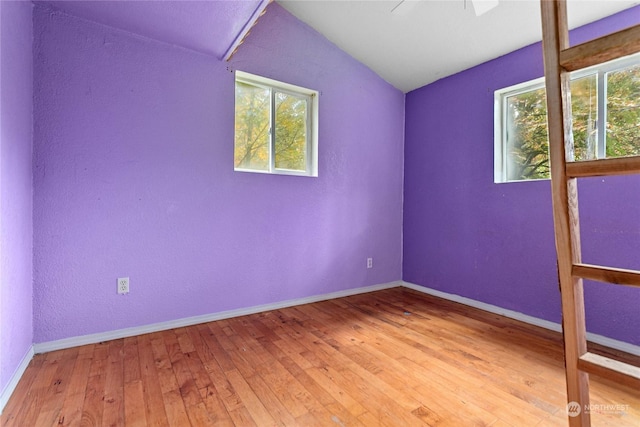 spare room featuring a healthy amount of sunlight, ceiling fan, lofted ceiling, and hardwood / wood-style floors