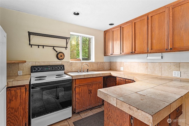 kitchen with backsplash, sink, light tile patterned floors, electric range, and tile counters