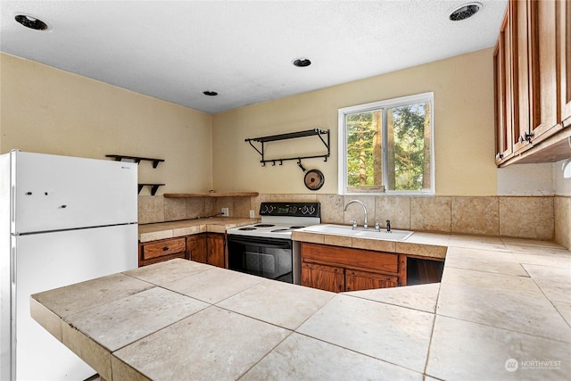 kitchen featuring tile countertops, decorative backsplash, white appliances, and sink