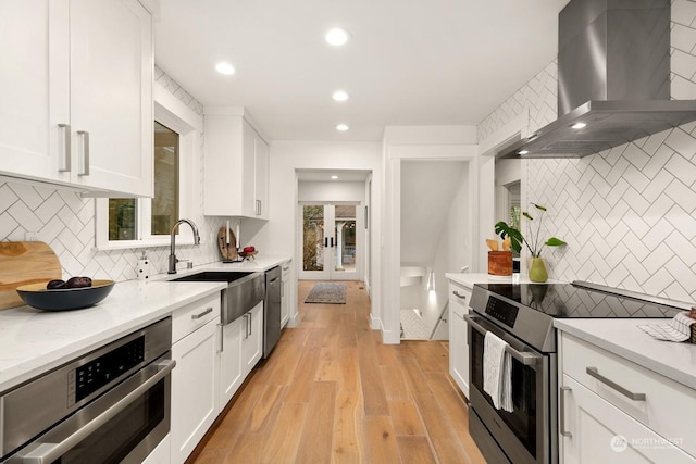 kitchen featuring white cabinetry, backsplash, wall chimney range hood, and stainless steel appliances