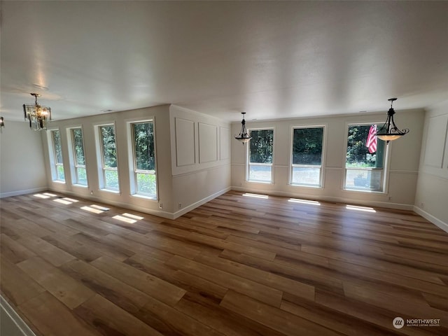 unfurnished living room featuring hardwood / wood-style floors and a chandelier