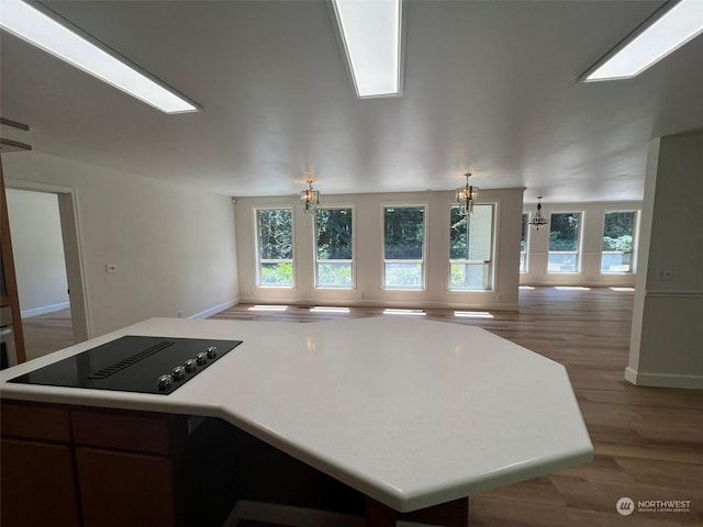 kitchen featuring black electric stovetop, wood-type flooring, and a chandelier