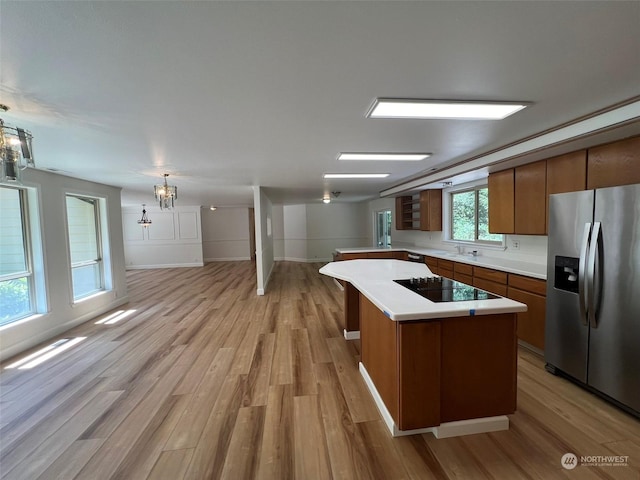 kitchen featuring a center island, light hardwood / wood-style flooring, stainless steel refrigerator with ice dispenser, decorative light fixtures, and black electric cooktop