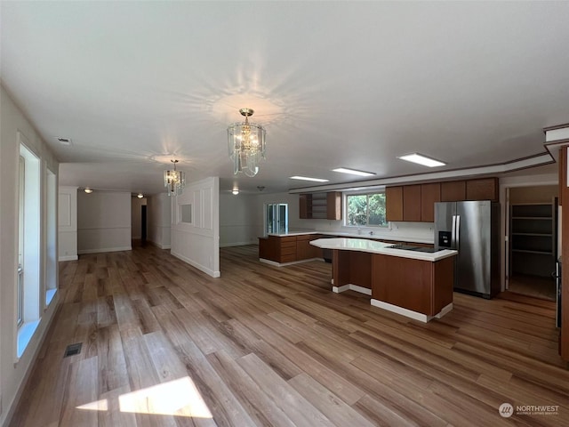 kitchen featuring pendant lighting, a spacious island, light hardwood / wood-style flooring, stainless steel fridge with ice dispenser, and a chandelier