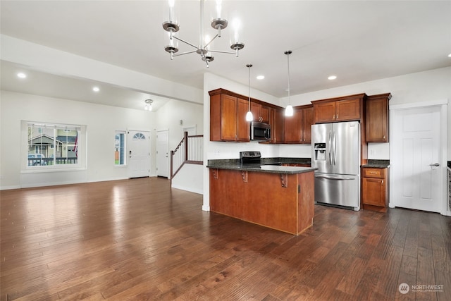 kitchen with dark wood-type flooring, stainless steel appliances, an inviting chandelier, pendant lighting, and a breakfast bar area