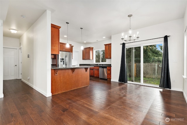 kitchen with a breakfast bar, dark hardwood / wood-style floors, stainless steel appliances, and decorative light fixtures