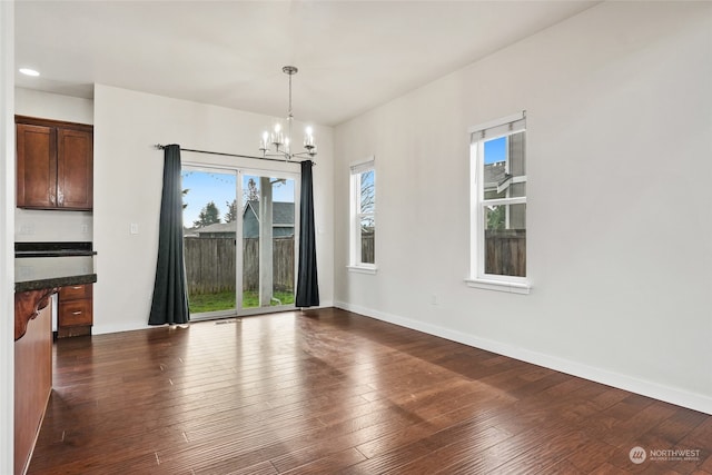 unfurnished dining area with dark hardwood / wood-style flooring and a chandelier