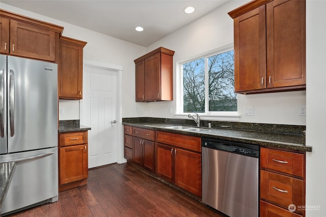 kitchen featuring dark stone countertops, sink, appliances with stainless steel finishes, and dark wood-type flooring