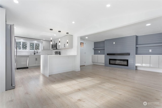 kitchen with a fireplace, pendant lighting, stainless steel appliances, and white cabinetry