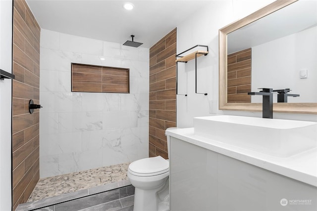 bathroom featuring tiled shower, vanity, and toilet