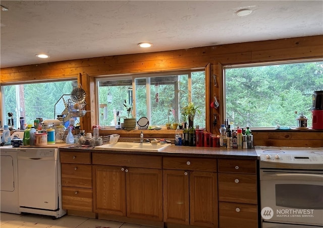 kitchen featuring sink, white dishwasher, a textured ceiling, light tile patterned flooring, and range