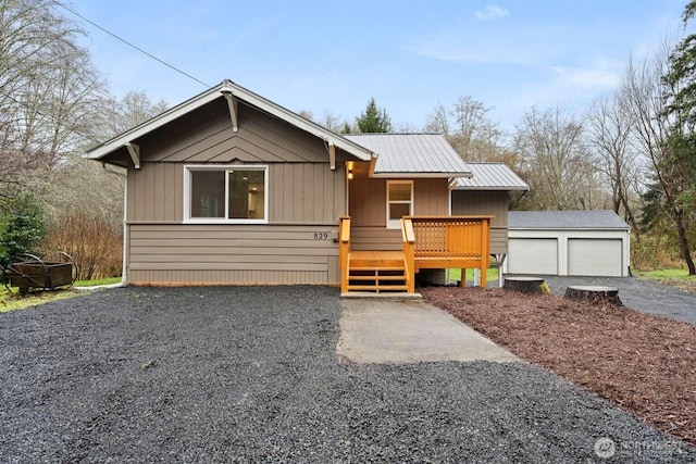 view of front of house featuring metal roof, an outdoor structure, a wooden deck, and a detached garage