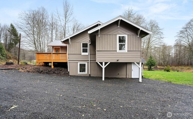 rear view of property with driveway, a deck, and board and batten siding