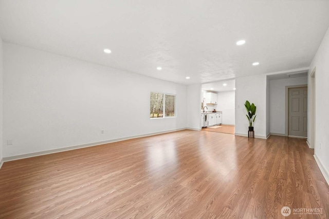 unfurnished living room with baseboards, light wood finished floors, and recessed lighting