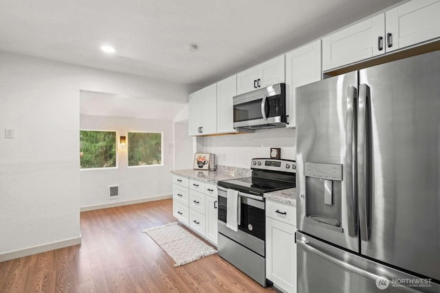 kitchen with visible vents, white cabinets, baseboards, appliances with stainless steel finishes, and light wood-type flooring