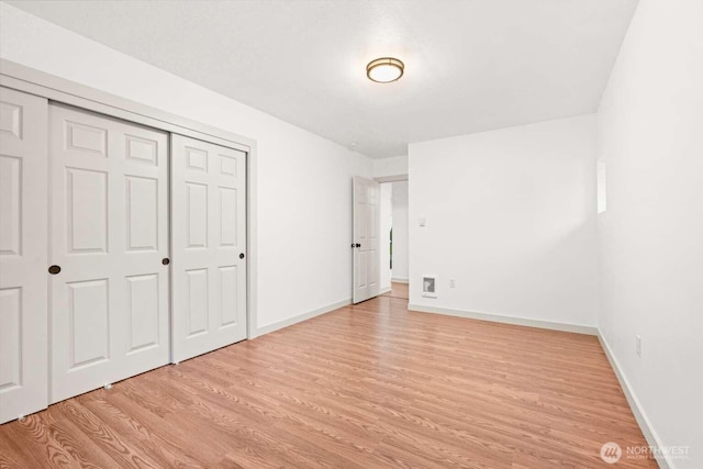 unfurnished bedroom featuring a closet, light wood-style flooring, and baseboards