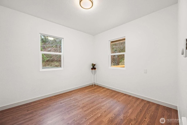 spare room with baseboards and wood finished floors