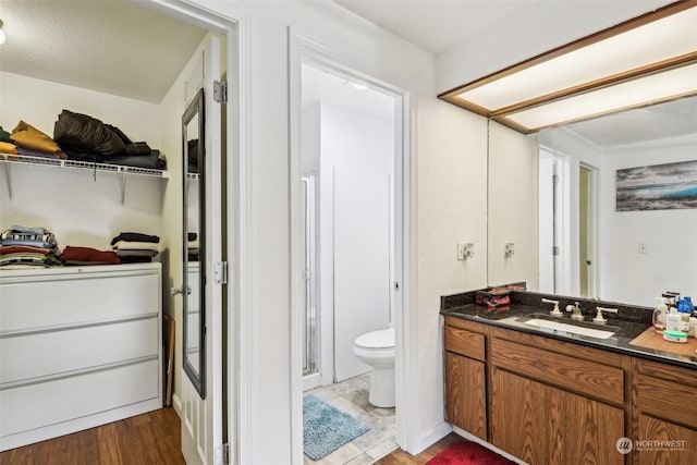 bathroom with hardwood / wood-style floors, vanity, toilet, and a shower with shower door