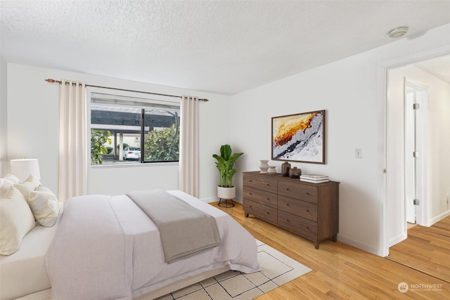 bedroom with light hardwood / wood-style floors and a textured ceiling