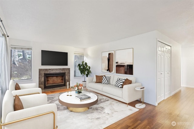 living room with wood-type flooring and a tiled fireplace