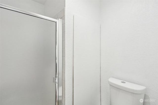 bathroom with a shower with door and toilet