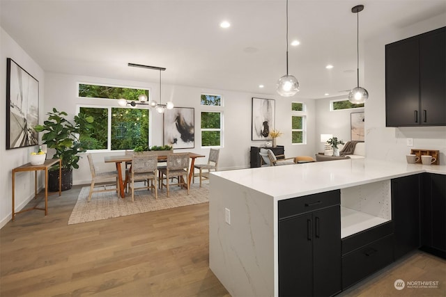 kitchen featuring kitchen peninsula, light hardwood / wood-style floors, decorative light fixtures, and an inviting chandelier