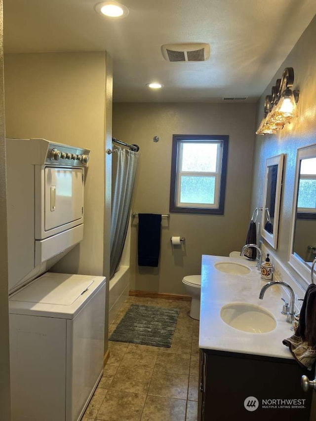 full bathroom featuring tile patterned floors, stacked washer / drying machine, toilet, vanity, and shower / bath combo