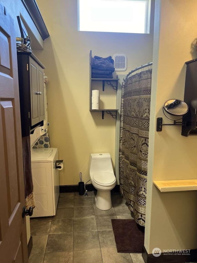 bathroom featuring tile patterned flooring, washer / clothes dryer, and toilet