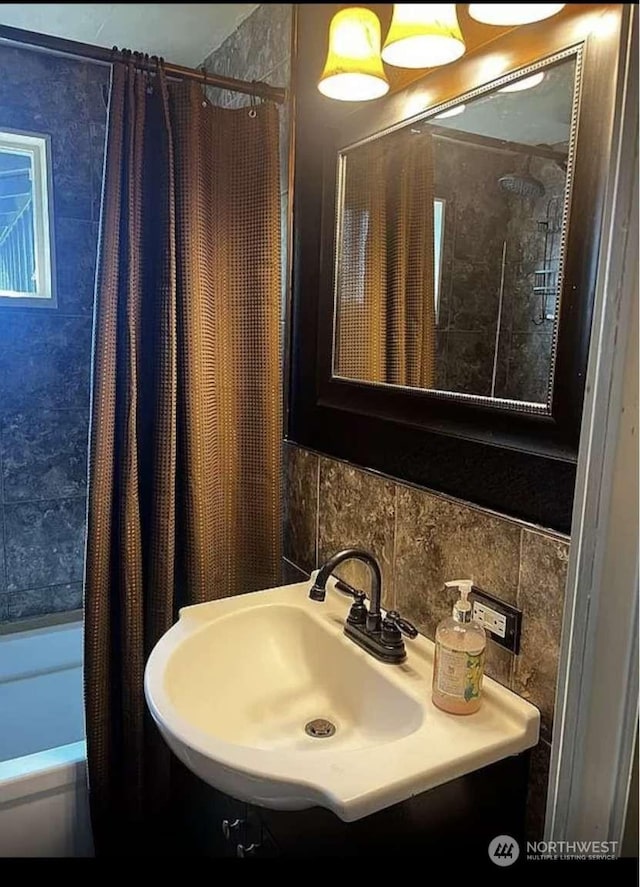 bathroom featuring shower / bathtub combination with curtain, sink, decorative backsplash, and tile walls