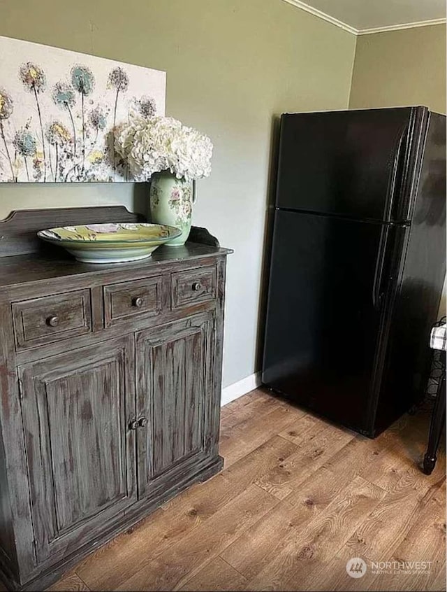 kitchen featuring black fridge, dark brown cabinets, and light hardwood / wood-style flooring