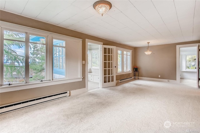 carpeted empty room with an inviting chandelier, a wealth of natural light, and a baseboard heating unit