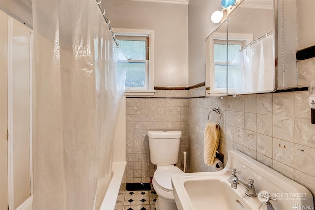 full bathroom with tile patterned flooring, toilet, plenty of natural light, and tile walls