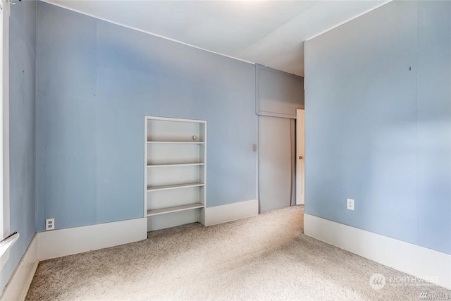 spare room with carpet and built in shelves