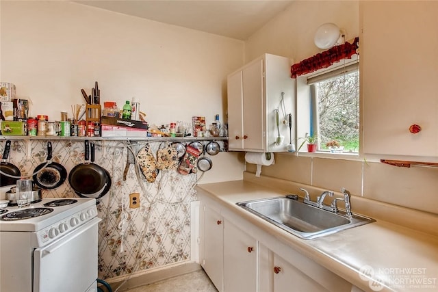 kitchen with backsplash, electric stove, white cabinetry, and sink