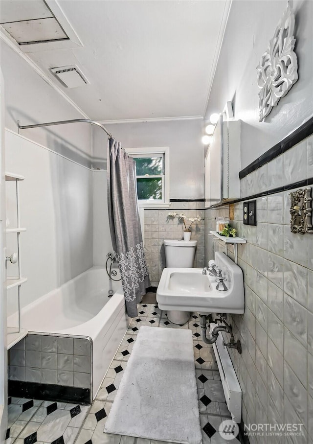 bathroom with toilet, a sink, visible vents, tile walls, and shower / bath combo with shower curtain