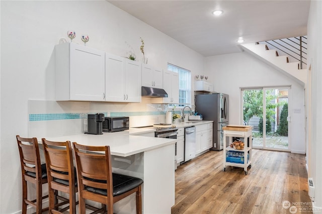 kitchen with a breakfast bar, white cabinetry, kitchen peninsula, and appliances with stainless steel finishes