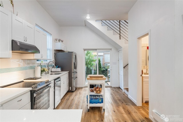 kitchen featuring appliances with stainless steel finishes, backsplash, sink, light hardwood / wood-style flooring, and white cabinets