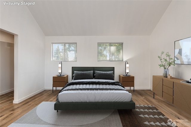 bedroom with light hardwood / wood-style floors, multiple windows, and vaulted ceiling