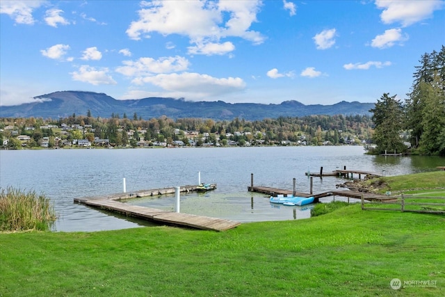 dock area featuring a lawn and a water and mountain view