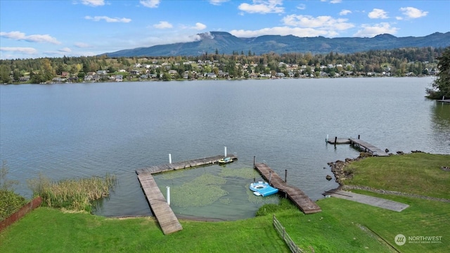 view of dock featuring a lawn and a water and mountain view