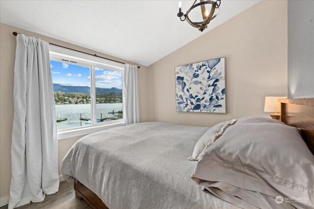 bedroom with lofted ceiling, wood-type flooring, multiple windows, and a water view