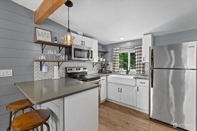 kitchen featuring decorative light fixtures, white cabinets, beamed ceiling, kitchen peninsula, and appliances with stainless steel finishes