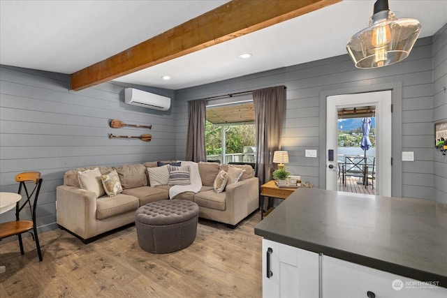 living room with light hardwood / wood-style flooring, beam ceiling, a wall mounted air conditioner, and plenty of natural light