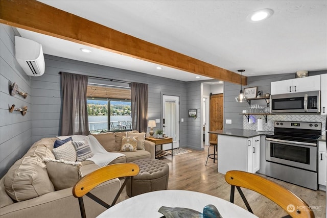 interior space with a barn door, appliances with stainless steel finishes, a wall mounted AC, white cabinets, and decorative light fixtures