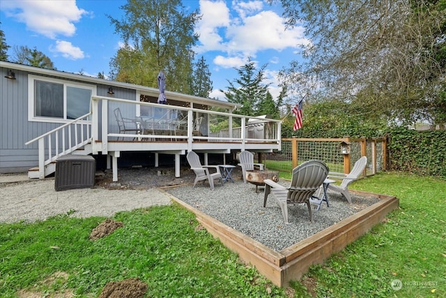 back of house featuring a deck, a fire pit, and a yard