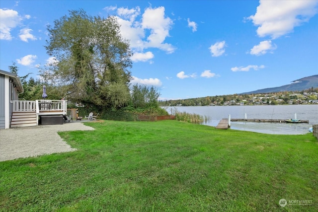 view of yard with a dock, a deck with water view, and a patio