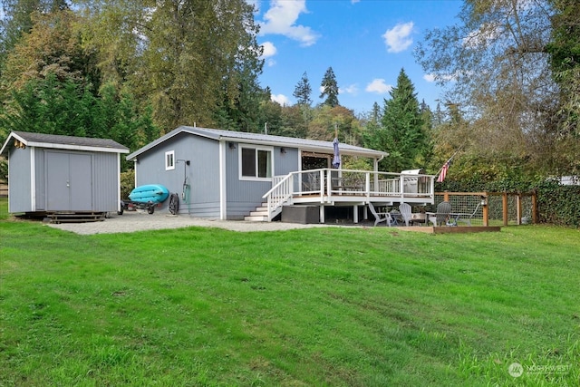 rear view of house featuring a shed, a yard, and a wooden deck