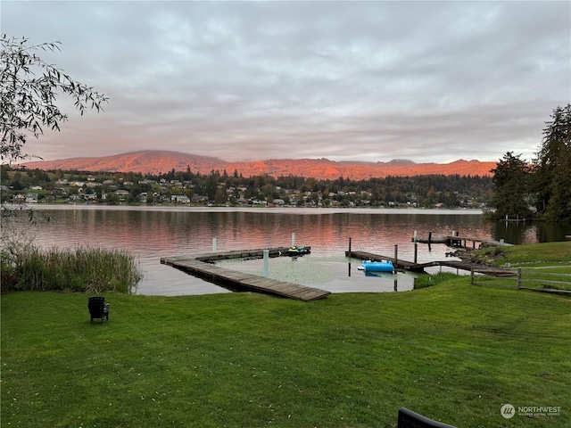 dock area featuring a water and mountain view and a lawn